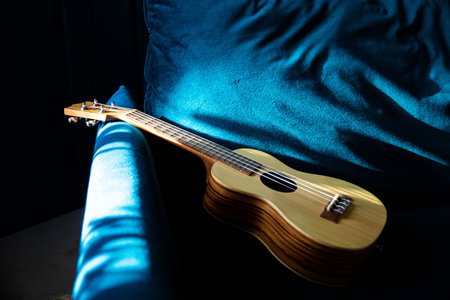 ukulele,  made of light wood, life style close-up, blue background.