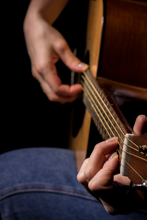 woman hand plays the guitar on black background, learning music. lifestyle
