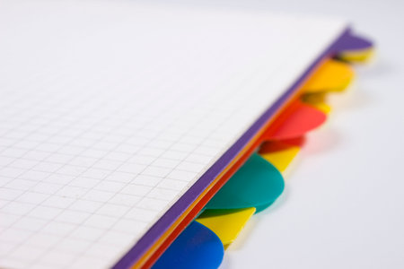 a notebook on a white background with colorful bookmarks sticking out of it. close-up