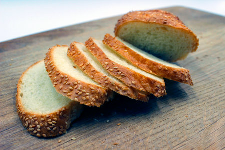Sliced bread lies on a dark board. Taken in close-up on a white background.