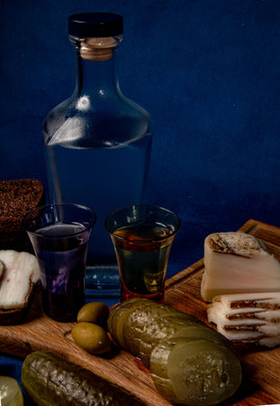 a bottle of alcohol surrounded by a variety of snacks on a dark blue background