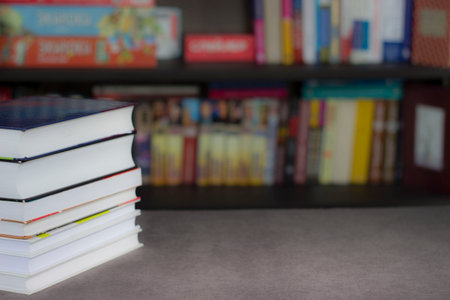 a stack of books on a library table with a bookcase in the background and a place for text, an...