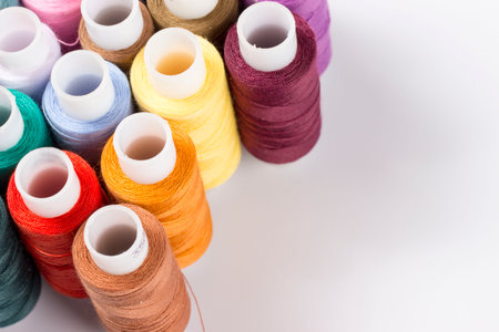 Multicolored sewing reels with threads stand on a white background. taken in close-up with space for...