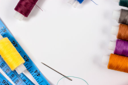 A tailor's centimeter or tapemeasure in blue, a sewing needle with threaded thread and multicolored...