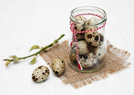 Quail eggs with willow branch on a old white wooden backgroundの写真素材