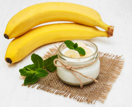 Banana with natural yoghurt on a old white wooden backgroundの写真素材
