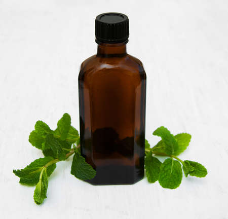 Bottle of mint oil and fresh mint  on a old wooden backgroundの写真素材