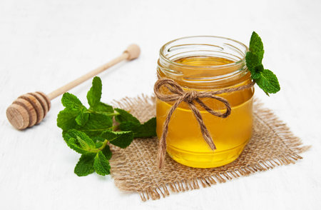 Honey with  mint on a old white wooden backgroundの写真素材