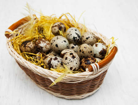Quail eggs in basket on a old white wooden backgroundの写真素材