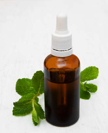 Bottle of mint oil and fresh mint  on a old wooden backgroundの写真素材