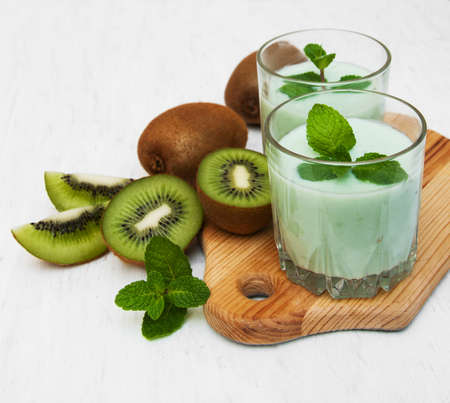 kiwi smoothie in glass on a old white wooden backgroundの写真素材
