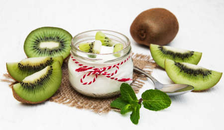 kiwi yogurt in glass on a old white wooden backgroundの写真素材