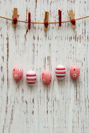 Easter eggs hanging on a line against the wooden background