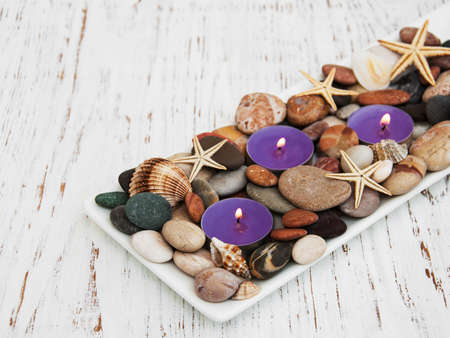 candles with sea pebbles, starfish and sea shells on wooden-backgroundの写真素材