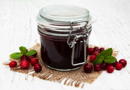 jar of cranberry jam with fresh fruits on a old wooden backgroundの写真素材