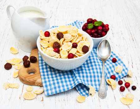 cornflakes with milk, cranberries and nuts on a wooden table