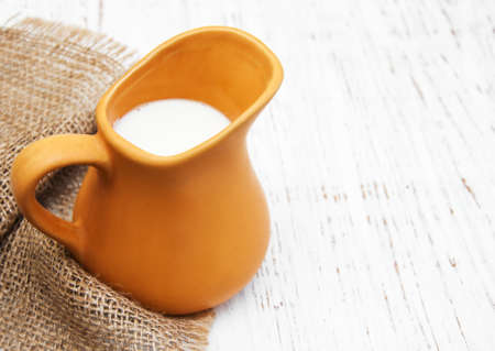 milk in pitcher on a old wooden backgroundの写真素材
