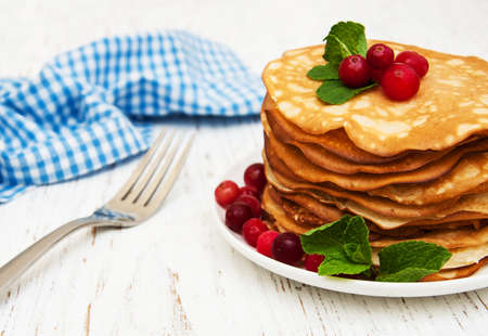 plate with pancakes with cranberries on a wooden backgroundの写真素材