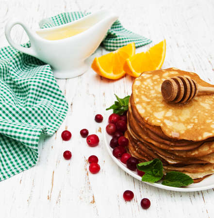 plate with pancakes with cranberries on a wooden backgroundの写真素材