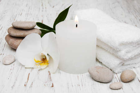 Candle, orcids and towels on a wooden backgroundの写真素材