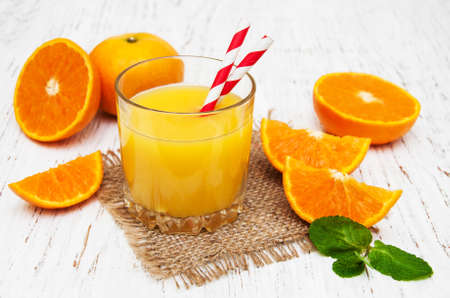 Orange juice and fresh oranges on a wooden backgroundの写真素材