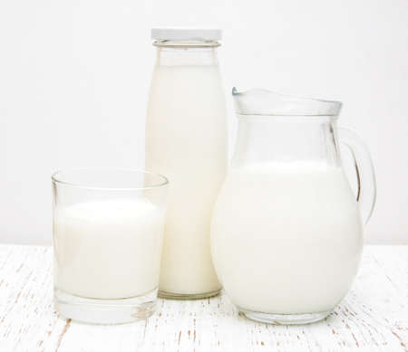 Jar, bottle and glass with fresh milk on a wooden backgroundの写真素材