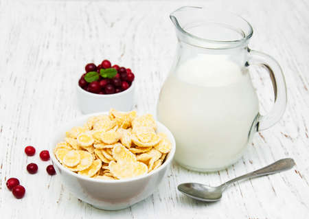 cornflakes with milk and cranberries on a wooden tableの写真素材