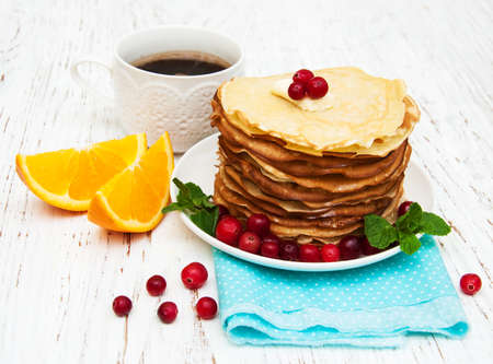 plate with pancakes with cranberries on a wooden backgroundの写真素材