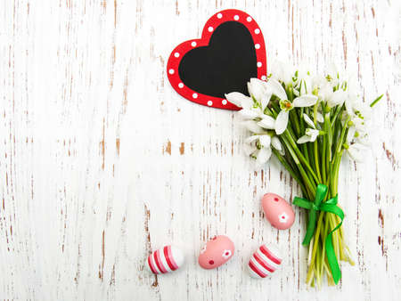 Eggs and spring snowdrops with board on a wooden backgroundの写真素材