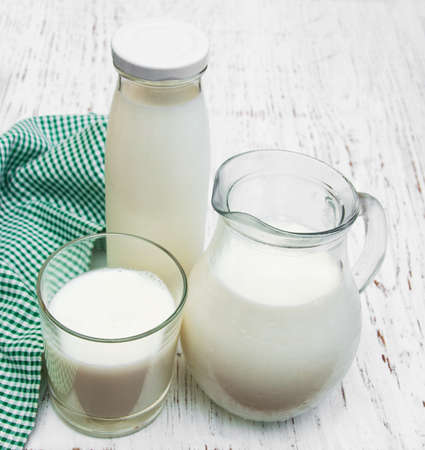 Jar, bottle and glass with fresh milk on a wooden backgroundの写真素材