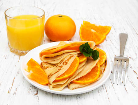 pancakes with orange and orange juice on a wooden tableの写真素材