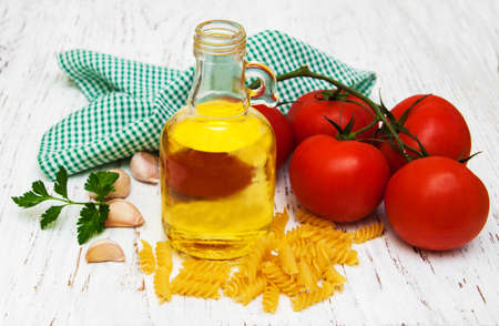 tomatoes, fusilli, garlic and olive oil on a old wooden tableの写真素材