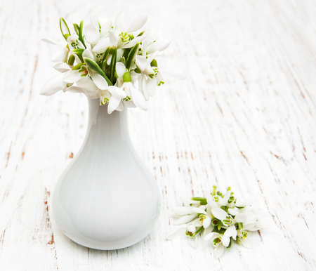 snowdrops in vase on a wooden backgroundの写真素材