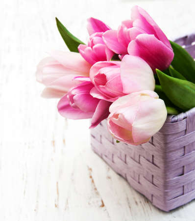 bouquet of pink tulips in a basket on a wooden backgroundの写真素材