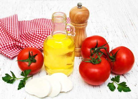olive oil, mozzarella cheese,  garlic and tomatoes on a wooden backgroundの写真素材