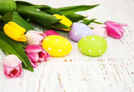 Tulips and easter eggs on a old wooden background