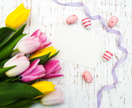 card with fresh flowers tulips and easter eggsの写真素材