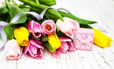 Tulips and gift box on a old wooden backgroundの写真素材