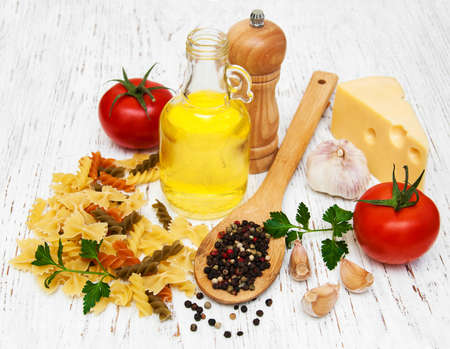 olive oil,  cheese, fusilli, garlic and tomatoes on a old wooden backgroundの写真素材