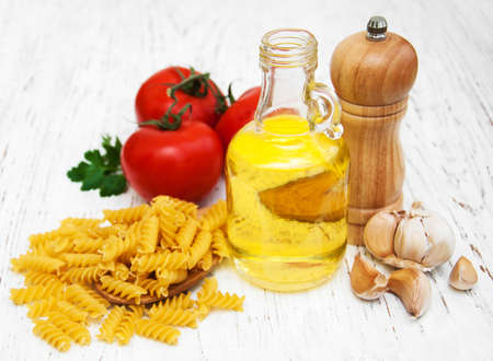 tomatoes, fusilli, garlic and olive oil on a old wooden tableの写真素材