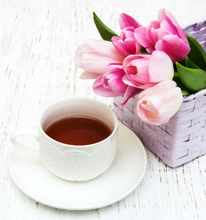 Cup of tea and pink tulips on a wooden backgroundの写真素材