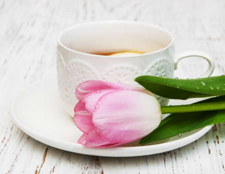 Cup of tea and pink tulips on a wooden backgroundの写真素材