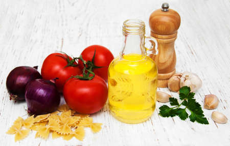 tomatoes, farfalle,  garlic and olive oil on a old wooden tableの写真素材