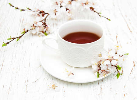 Cup of tea and spring apricot blossom on a wooden backgroundの写真素材