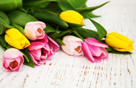 border of pink and yellow tulips  on a wooden backgroundの写真素材