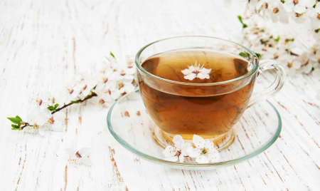 Cup of tea and spring apricot blossom on a wooden backgroundの写真素材