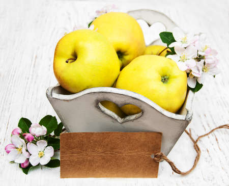 box with apples  and apple tree blossoms and empty tag on a  wooden tableの写真素材