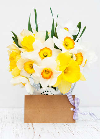 Yellow daffodils in a vase with empty tag on a old wooden backgroundの写真素材