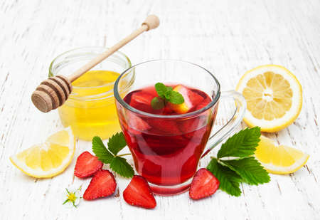 Fruit tea with strawberries and honey on a wooden tableの写真素材