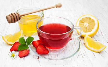 Fruit tea with strawberries and honey on a wooden tableの写真素材